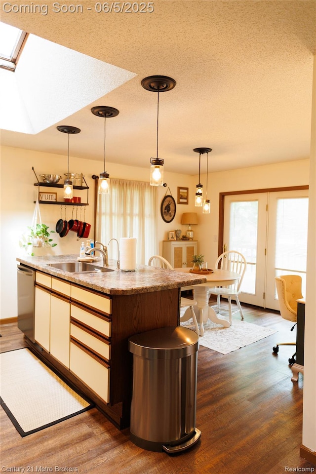 4447 Stanley Rd, Genesee, MI 48437 - kitchen with stainless steel dishwasher, wood finished floors, hanging light fixtures, a sink, and a textured ceiling