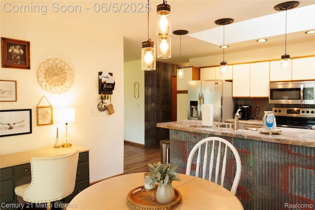 4447 Stanley Rd, Genesee, MI 48437 - kitchen featuring stainless steel appliances, white cabinetry, decorative light fixtures, wood finished floors, and backsplash