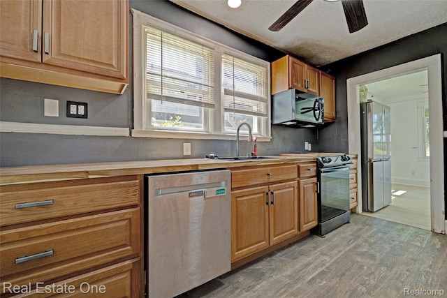 86 Marquette St, Pontiac, MI 48342 - kitchen with stainless steel appliances, light wood finished floors, a ceiling fan, a sink, and brown cabinetry