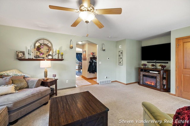 2567 Chippewa Trl, Muskegon, MI 49445 - living room featuring carpet, a ceiling fan, arched walkways, a glass covered fireplace, and baseboards
