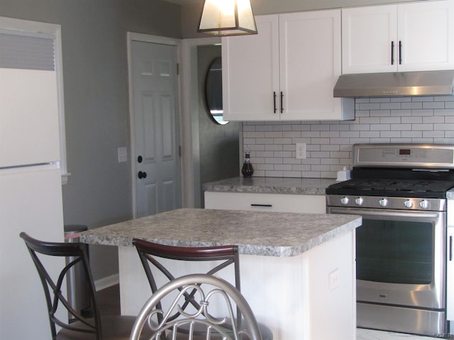736 State St, Adrian, MI 49221 - kitchen with stainless steel range with gas cooktop, under cabinet range hood, freestanding refrigerator, backsplash, and white cabinetry