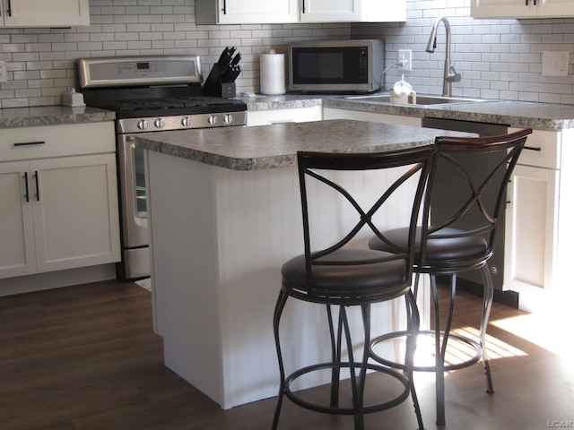736 State St, Adrian, MI 49221 - kitchen featuring stainless steel appliances, dark wood finished floors, decorative backsplash, and white cabinetry