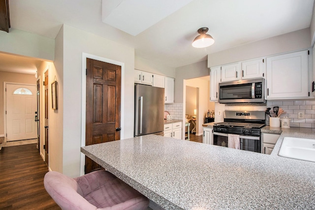 3025 Juneberry Ave SE, Grand Rapids, MI 49508 - kitchen featuring appliances with stainless steel finishes, a peninsula, decorative backsplash, white cabinets, and a breakfast bar area