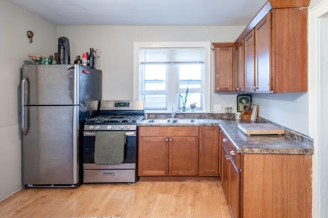 733 Lafayette Ave NE, Grand Rapids, MI 49503 - kitchen with stainless steel appliances, dark countertops, brown cabinetry, light wood-type flooring, and a sink
