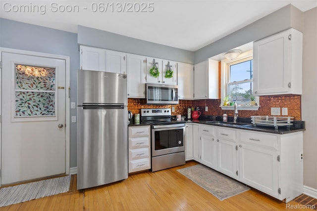 1 Jones St, Yale, MI 48097 - kitchen featuring appliances with stainless steel finishes, a sink, dark countertops, white cabinets, and light wood-style floors