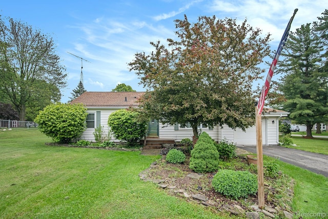 613 Genesee Ave, Gaines, MI 48436 - view of property hidden behind natural elements featuring a front lawn, asphalt driveway, and a garage