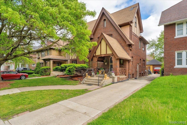 2505 Chicago Blvd, Detroit, MI 48206 - tudor-style house featuring covered porch, roof with shingles, a front lawn, and brick siding
