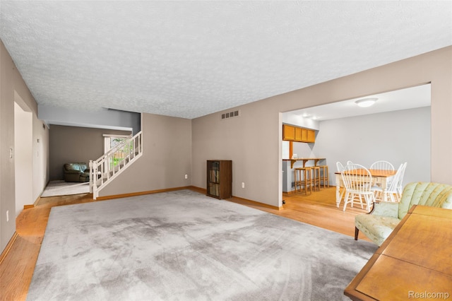 5138 Bayside Dr, Troy, MI 48098 - unfurnished living room featuring stairs, wood finished floors, baseboards, and a textured ceiling