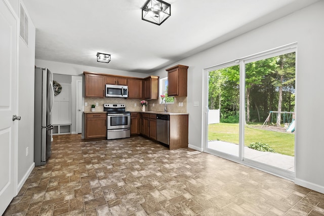 10126 Castle Creek Cir, Galesburg, MI 49053 - kitchen with stainless steel appliances, backsplash, light countertops, baseboards, and stone finish flooring