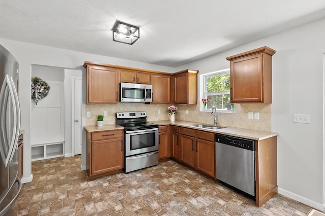 10126 Castle Creek Cir, Galesburg, MI 49053 - kitchen with stainless steel appliances, a sink, decorative backsplash, and brown cabinetry