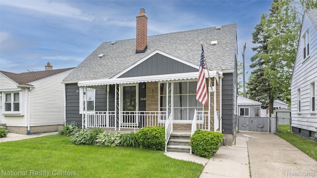 3446 17th St, Wyandotte, MI 48192 - view of front of house with covered porch, a shingled roof, a chimney, and board and batten siding