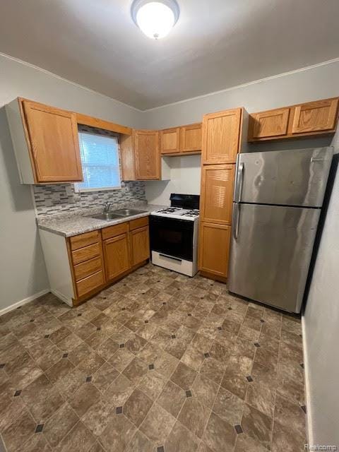 1010 S Garden St, Flint, MI 48503 - kitchen featuring white range with gas stovetop, freestanding refrigerator, a sink, light countertops, and tasteful backsplash