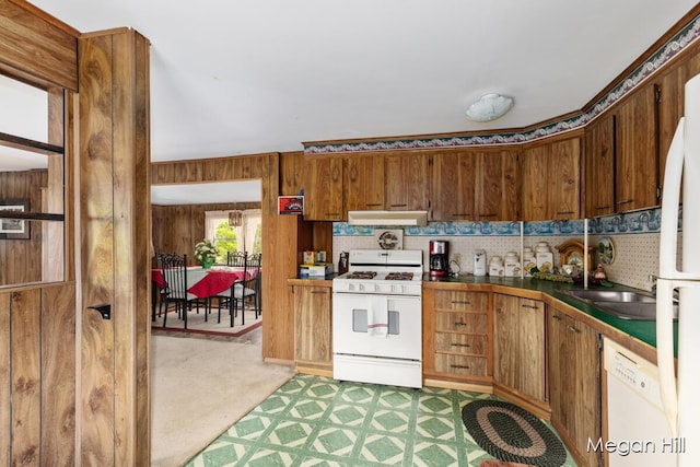 3570 109th Ave, Allegan, MI 49010 - kitchen featuring white appliances, under cabinet range hood, light colored carpet, brown cabinets, and wood walls