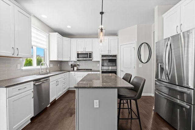 310 Fletcher St, Wixom, MI 48393 - kitchen featuring stainless steel appliances, a sink, dark wood-style flooring, a kitchen island, and a kitchen bar