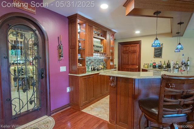 72755 Solanus Dr, Bruce, MI 48065 - indoor wet bar featuring hanging light fixtures, light wood-style floors, recessed lighting, tasteful backsplash, and arched walkways