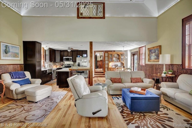 6624 Jefferson Rd, North Branch, MI 48461 - living area with a wainscoted wall, light wood-type flooring, wood walls, ceiling fan, and a high ceiling
