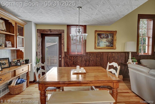 6624 Jefferson Rd, North Branch, MI 48461 - dining space featuring light wood-type flooring, an ornate ceiling, wainscoting, and wooden walls