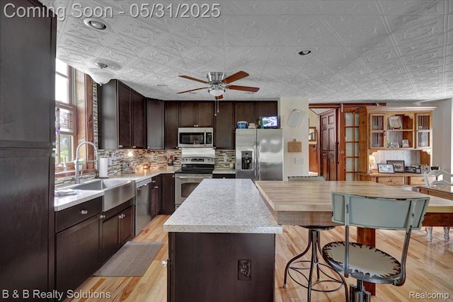 6624 Jefferson Rd, North Branch, MI 48461 - kitchen featuring appliances with stainless steel finishes, decorative backsplash, light countertops, light wood-style floors, and an ornate ceiling