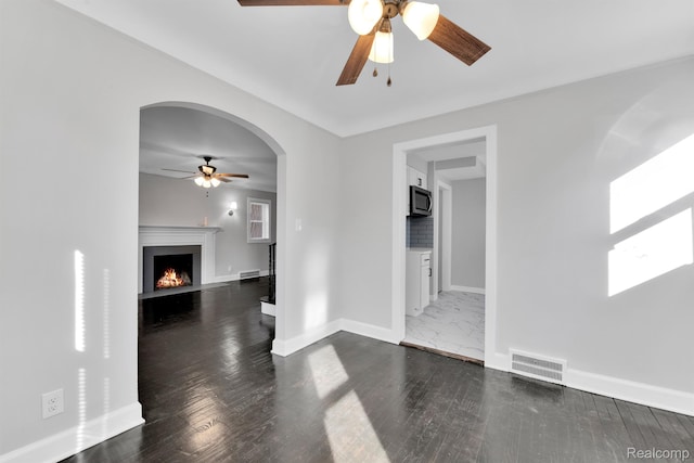 15480 Asbury Park, Detroit, MI 48227 - unfurnished living room featuring ceiling fan, baseboards, a fireplace with flush hearth, arched walkways, and dark wood-style floors