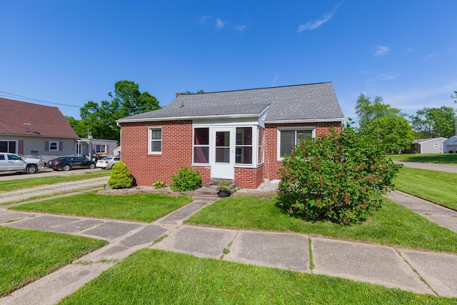 113 Greenleaf St, Onsted, MI 49265 - bungalow-style home with brick siding, a front yard, and roof with shingles