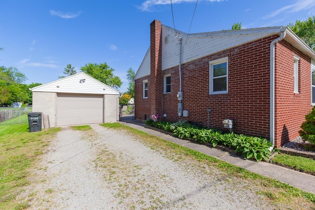 113 Greenleaf St, Onsted, MI 49265 - view of home's exterior with a chimney, an outdoor structure, brick siding, dirt driveway, and a garage