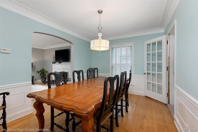 480 Fisher Rd, Grosse Pointe Farms, MI 48230 - dining space featuring a decorative wall, crown molding, wainscoting, arched walkways, and light wood finished floors
