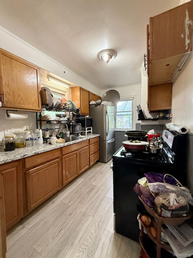 6507 Penrod St, Dearborn, MI 48228 - kitchen with range with electric cooktop, freestanding refrigerator, light wood finished floors, brown cabinetry, and a sink