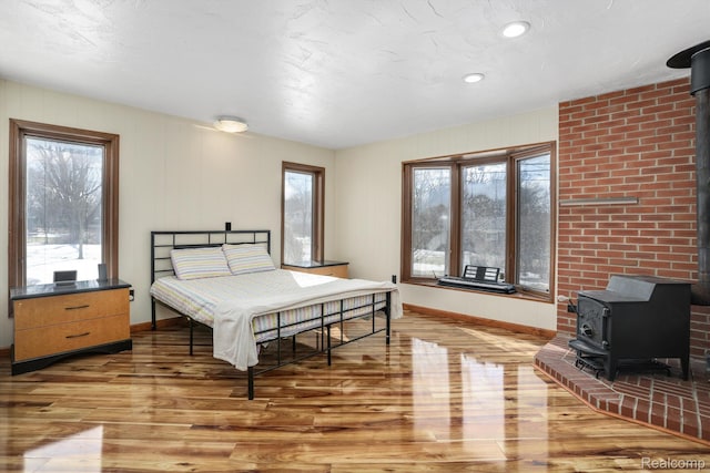 4173 Brandywyne Dr, Troy, MI 48098 - bedroom with a wood stove, light wood-type flooring, multiple windows, baseboards, and recessed lighting