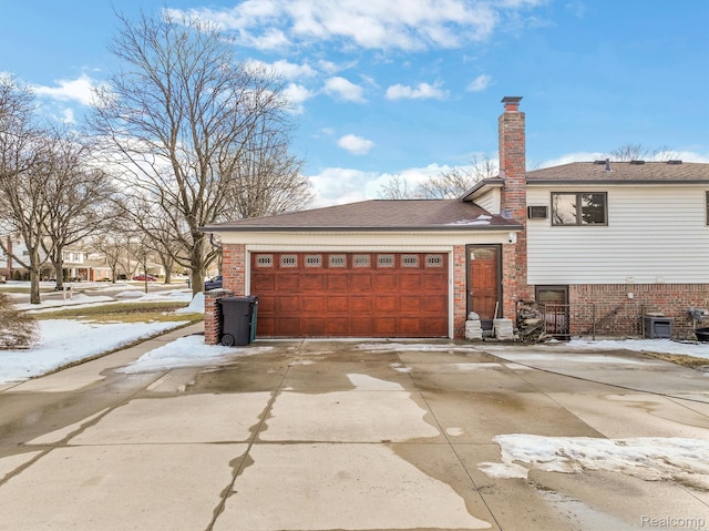 4173 Brandywyne Dr, Troy, MI 48098 - view of snowy exterior with an attached garage, driveway, a chimney, and brick siding