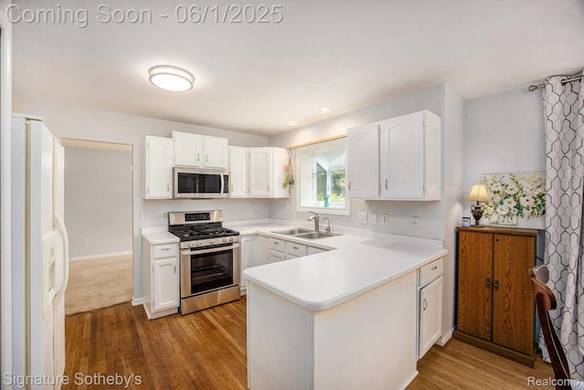 7674 Woodside Pl, Waterford, MI 48327 - kitchen with stainless steel appliances, a peninsula, white cabinetry, and wood finished floors