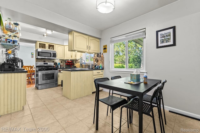 7485 Pointe Dr, Canton, MI 48187 - kitchen featuring stainless steel appliances, cream cabinetry, dark countertops, decorative backsplash, and a peninsula