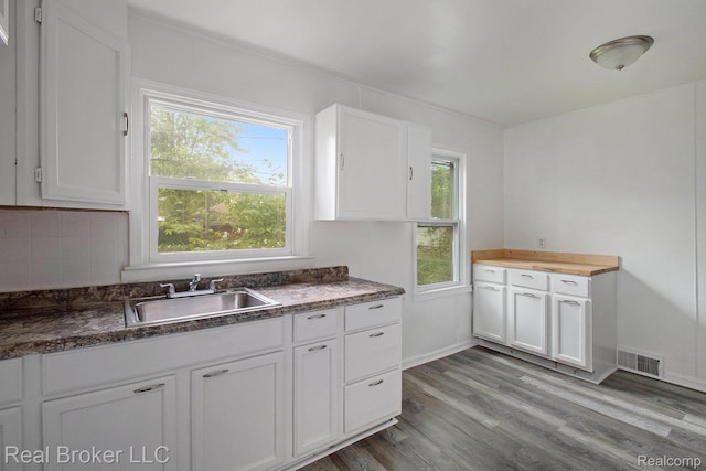 19455 Houghton St, Detroit, MI 48219 - kitchen with a sink, white cabinetry, wood finished floors, dark countertops, and decorative backsplash