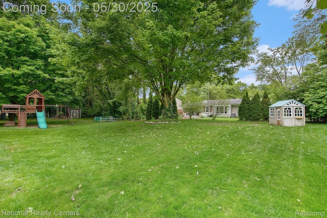 44947 Partridge Dr, Plymouth, MI 48170 - view of grassy yard with a playground and view of wooded area