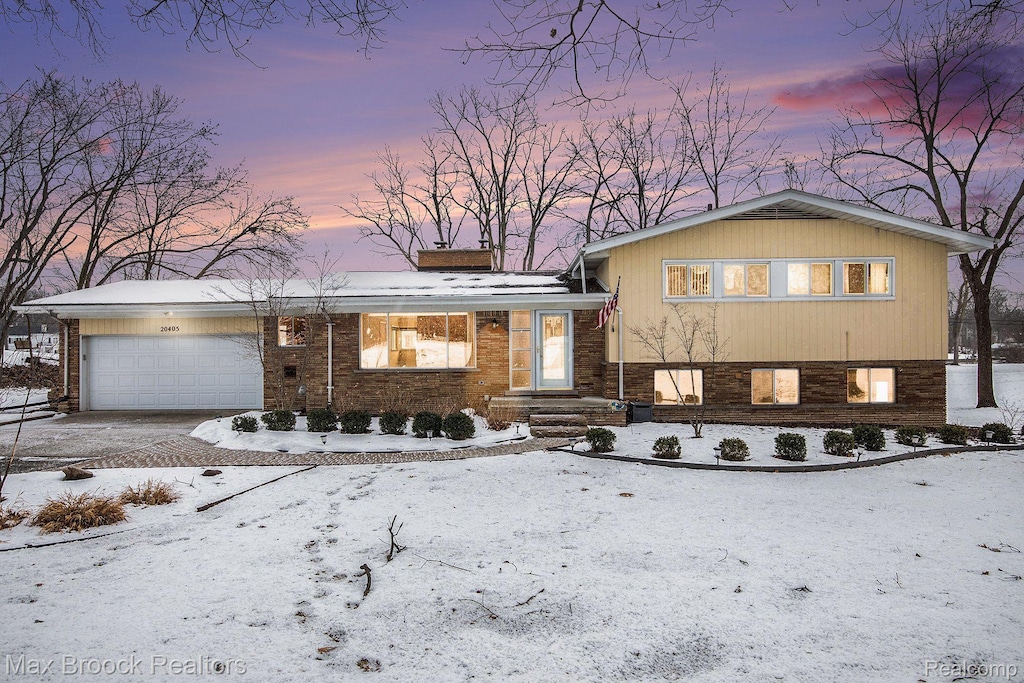 20405 Thorofare Rd, Grosse Ile, MI 48138 - split level home featuring a chimney, a garage, driveway, and brick siding