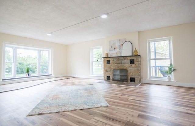 1658 Joslyn Rd, Muskegon, MI 49445 - unfurnished living room featuring healthy amount of natural light, wood finished floors, a fireplace, recessed lighting, and a textured ceiling