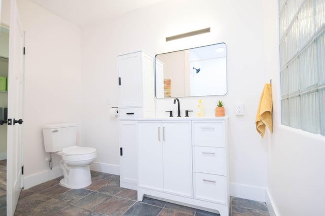 1658 Joslyn Rd, Muskegon, MI 49445 - bathroom with baseboards, toilet, vanity, and stone tile floors