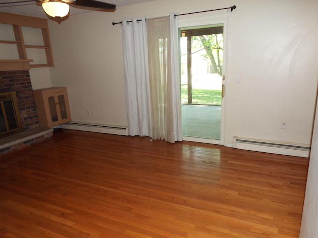407 Doty St, Leslie, MI 49251 - unfurnished living room with a baseboard heating unit, light wood finished floors, a fireplace, and ceiling fan
