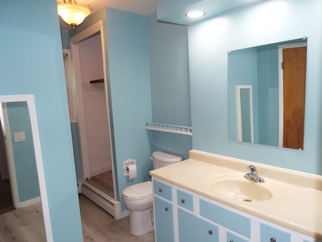 407 Doty St, Leslie, MI 49251 - bathroom featuring a baseboard radiator, toilet, vanity, wood finished floors, and a stall shower