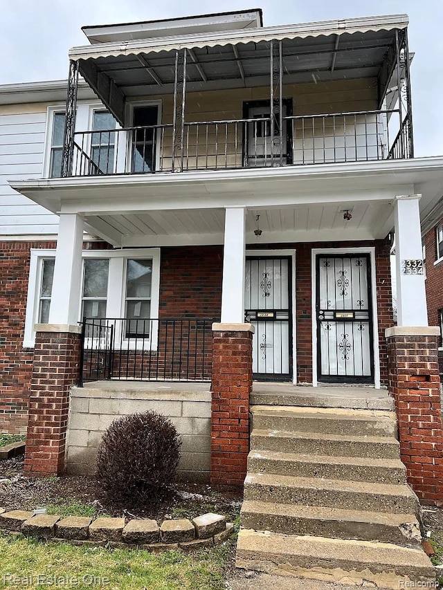 2332 Clements St, Detroit, MI 48238 - view of exterior entry featuring a balcony, brick siding, and a porch