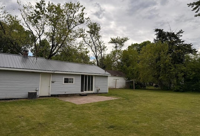 3924 Oakland Dr, Kalamazoo, MI 49008 - back of house featuring a lawn, a patio, metal roof, central AC, and a chimney