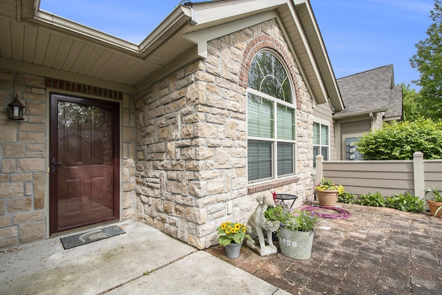933 Bridge Crest Dr SE, Ada, MI 49301 - entrance to property with stone siding, a patio area, and a shingled roof