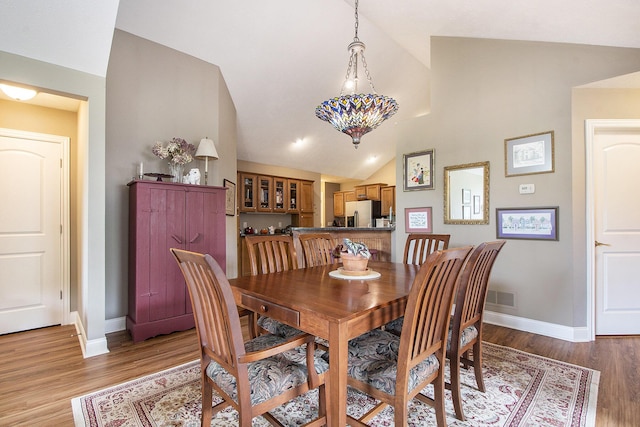 933 Bridge Crest Dr SE, Ada, MI 49301 - dining room with vaulted ceiling, baseboards, and light wood-style flooring