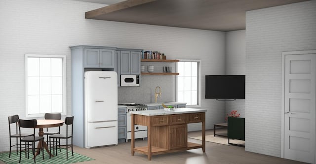 1000 Garfield Ave NW, Grand Rapids, MI 49504 - kitchen with white appliances, open shelves, light wood-type flooring, light countertops, and a kitchen island