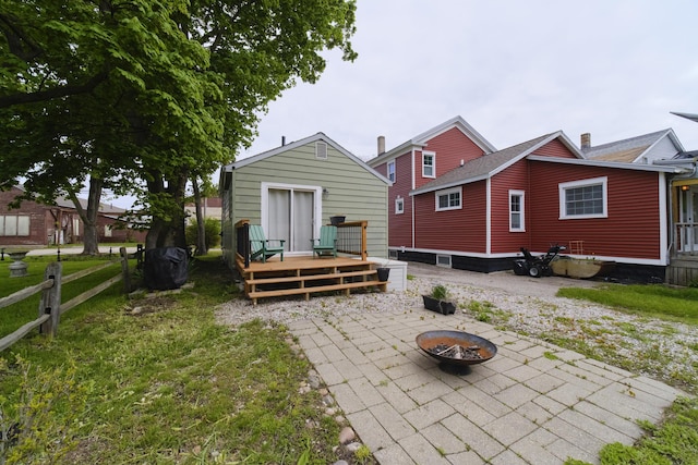 513 1st St, Manistee, MI 49660 - rear view of property with an outdoor fire pit, a wooden deck, a patio area, and a yard