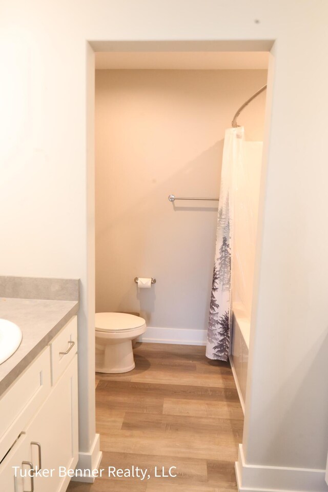 239 Monroe Ave, Muskegon, MI 49441 - bathroom featuring toilet, wood finished floors, vanity, and baseboards