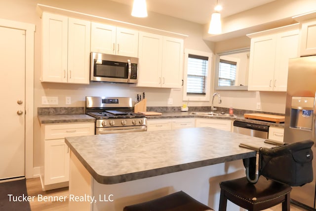 239 Monroe Ave, Muskegon, MI 49441 - kitchen featuring appliances with stainless steel finishes, a sink, a breakfast bar, white cabinets, and a kitchen island