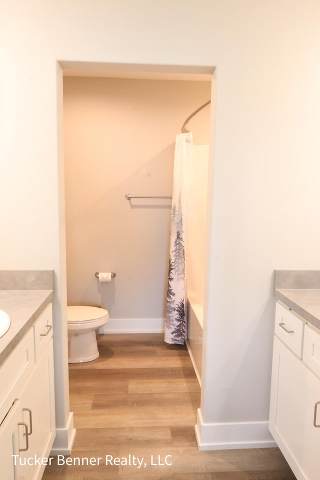 239 Monroe Ave, Muskegon, MI 49441 - full bathroom featuring vanity, toilet, wood finished floors, baseboards, and shower / tub combo