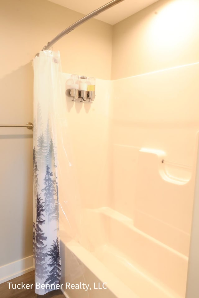 239 Monroe Ave, Muskegon, MI 49441 - bathroom with shower / tub combo with curtain, wood finished floors, and baseboards