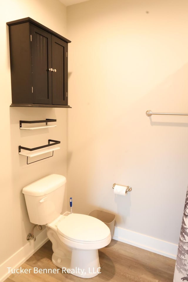 239 Monroe Ave, Muskegon, MI 49441 - bathroom featuring baseboards, toilet, and wood finished floors