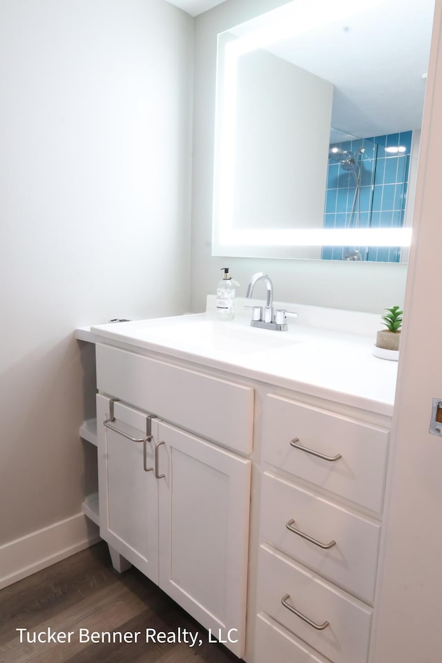 239 Monroe Ave, Muskegon, MI 49441 - bathroom with vanity, wood finished floors, and baseboards